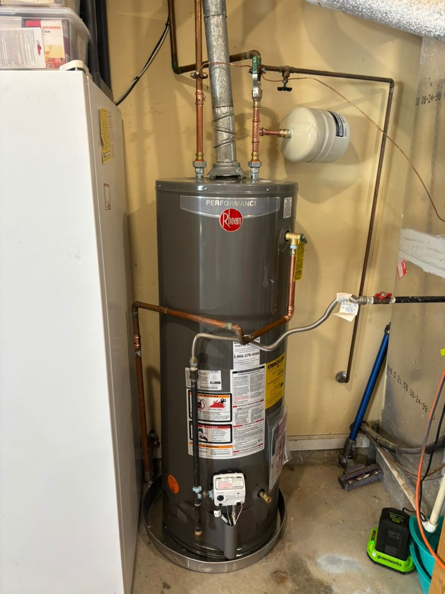 Water heater in a utility closet beside a furnace, with copper pipes and a gas line.