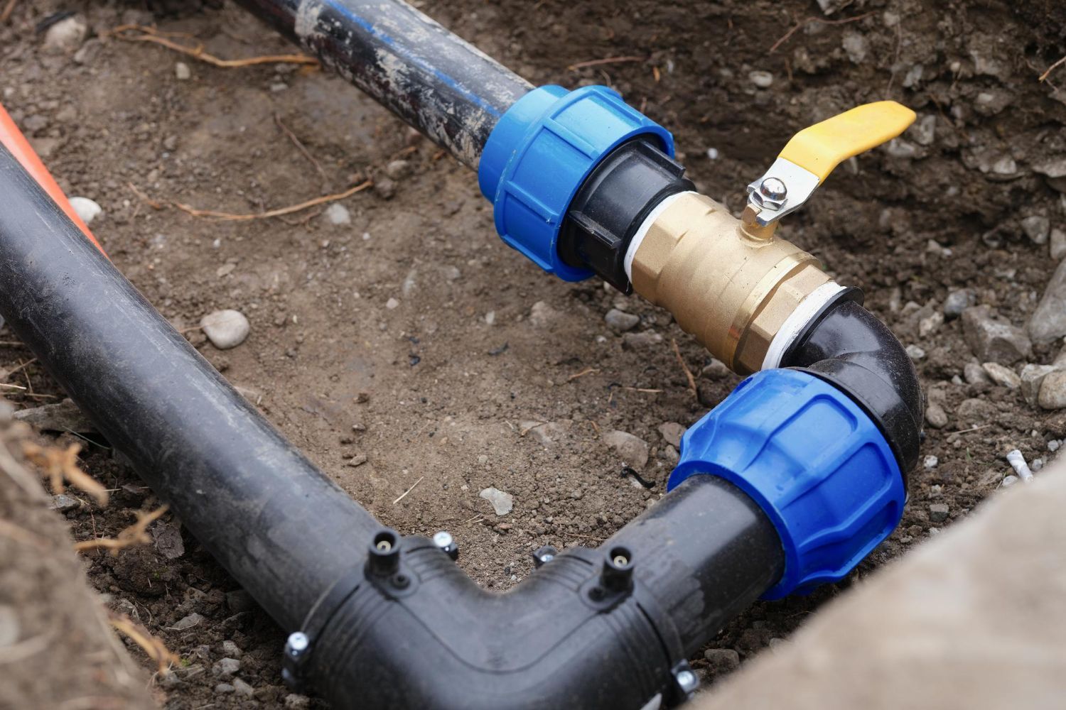 A close up of a water pipe being installed in the ground.