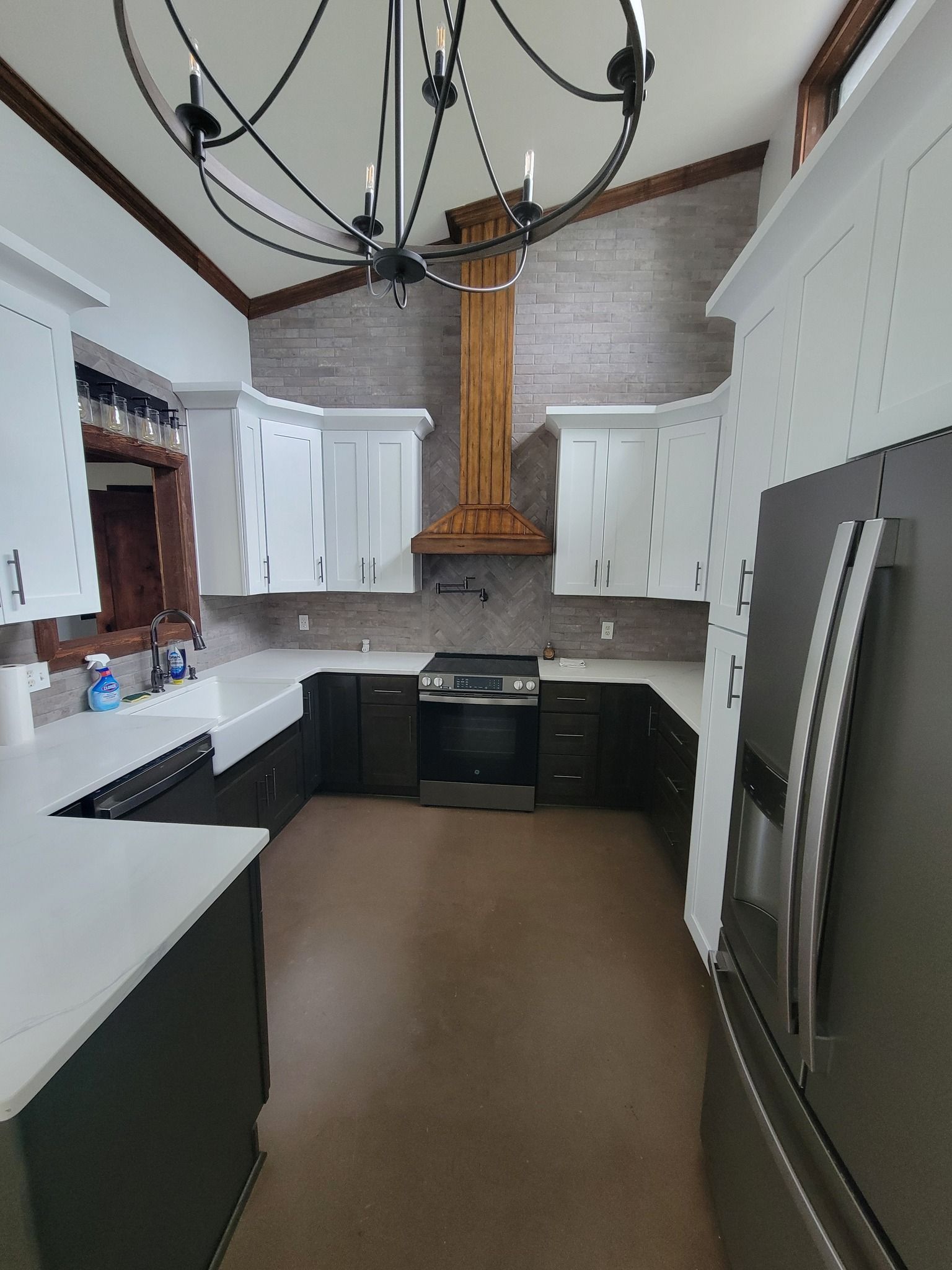 Modern kitchen with white cabinets, black countertops, stainless fridge, and copper range hood