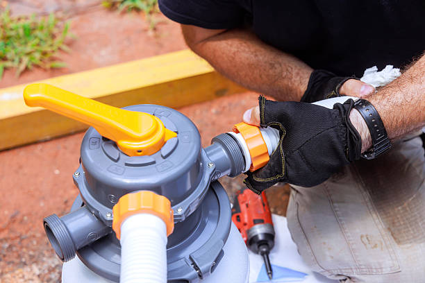A man is fixing a pool filter with a drill.