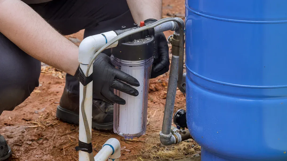 A person is installing a water filter in a water tank.