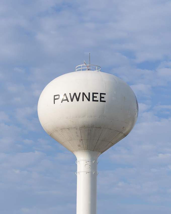 White water tower labeled “PAWNEE” against a partly cloudy blue sky.