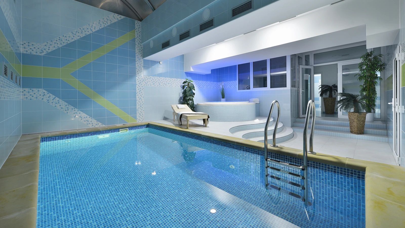 A large indoor swimming pool with a jacuzzi in the background.