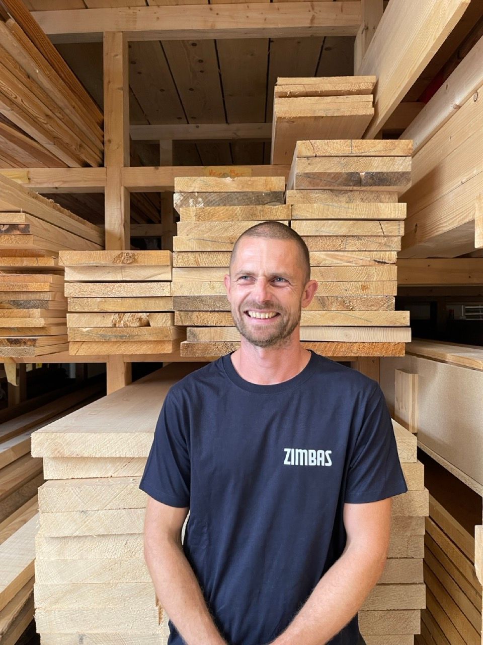 A man in an apron is smiling in a workshop.