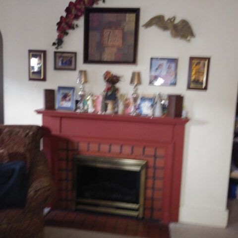 Red fireplace mantel with framed photos and decorative items in a living room