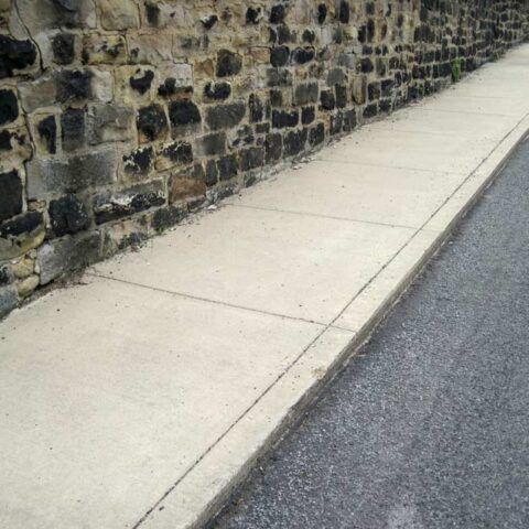 Stone retaining wall beside a concrete sidewalk and asphalt road