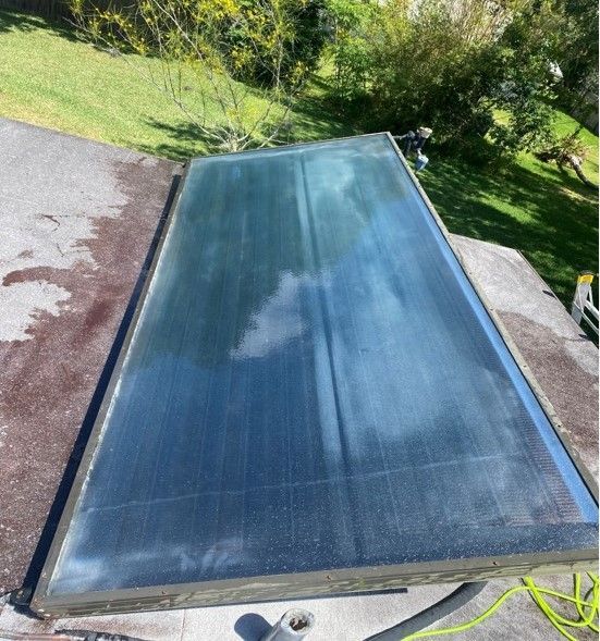 Rectangular solar pool cover on a patio, reflecting clouds and sky.