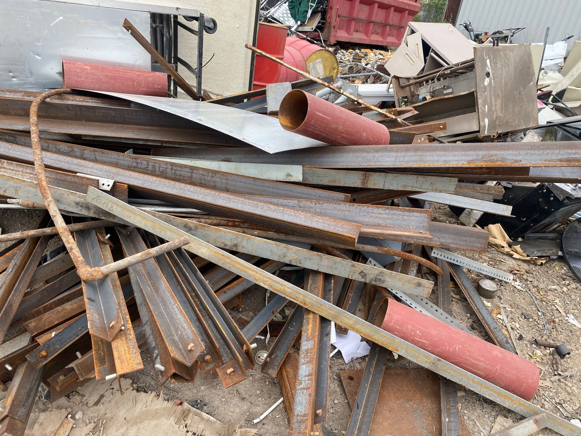 Pile of scrap metal and debris with rusted pipes and beams in an outdoor junkyard.