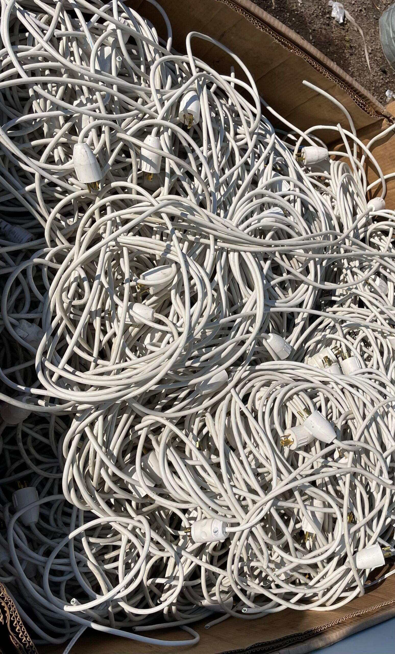 A box filled with tangled white cables or cords