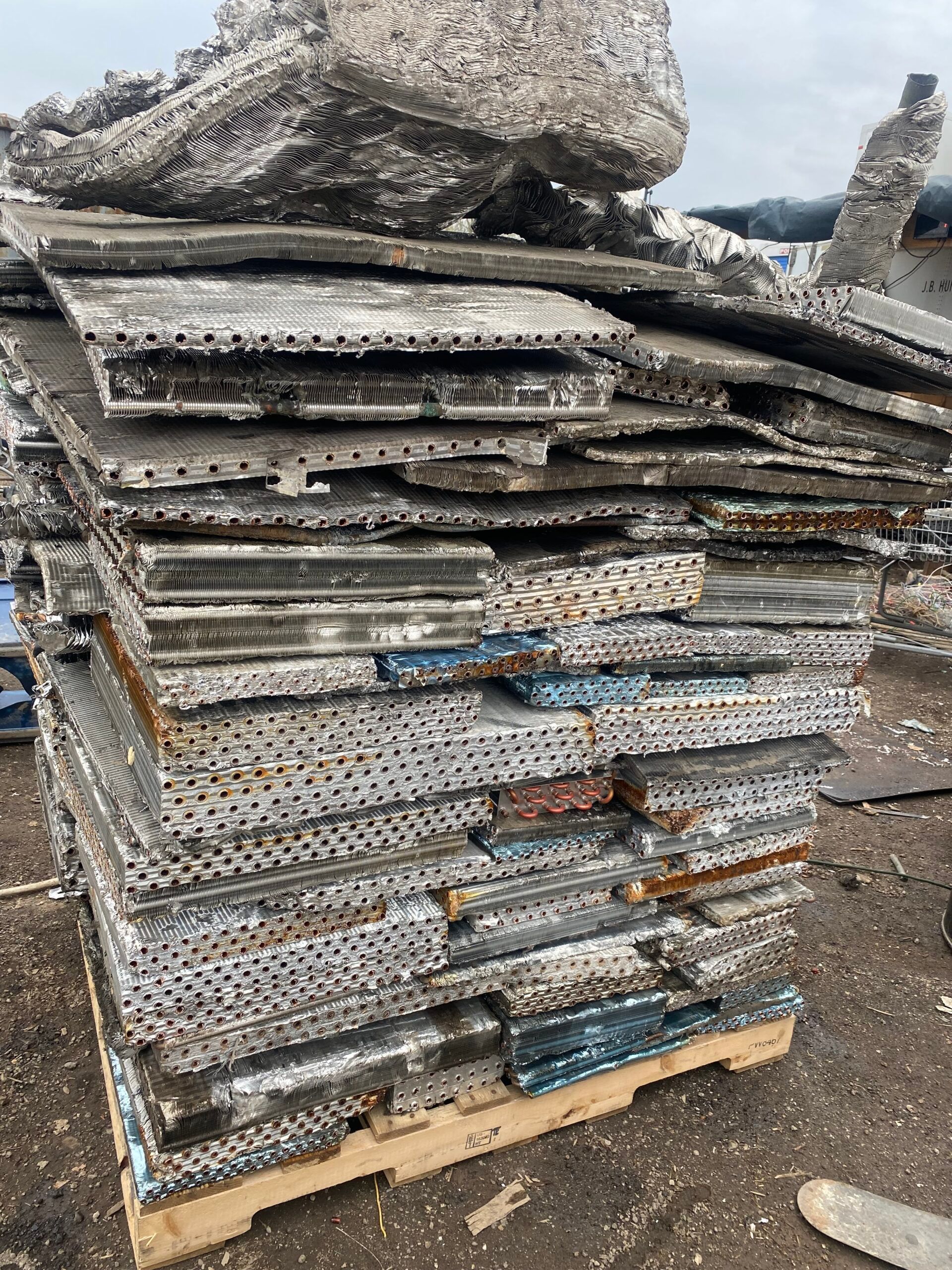 Stack of weathered concrete slabs on a pallet outdoors, with a large rock on top.