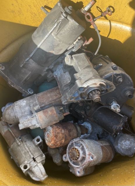 Pile of used electric motors and metal parts in a yellow bin.