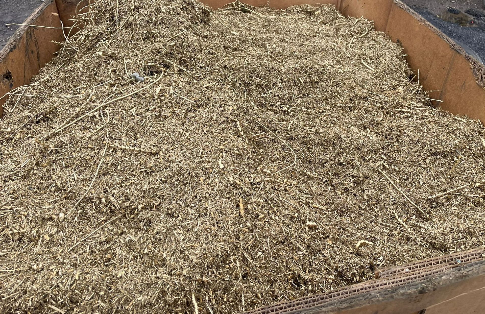 A large pile of brown wood shavings in a wooden container