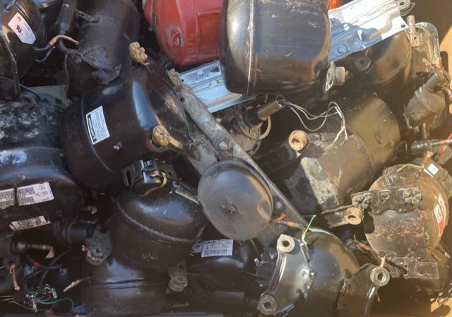 Pile of black and dark metal automotive parts and scraps in a junkyard-like setting