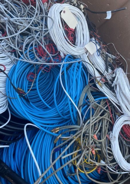 Tangled bundles of blue, white, and gray cables piled together outdoors
