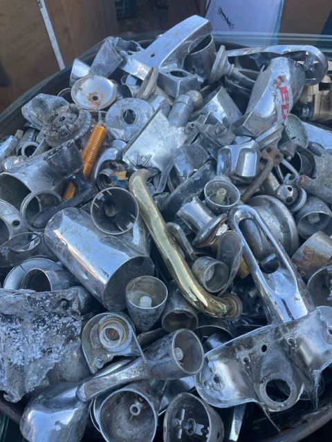 Pile of mixed scrap metal parts and pipes in a bin, mostly silver and gray.