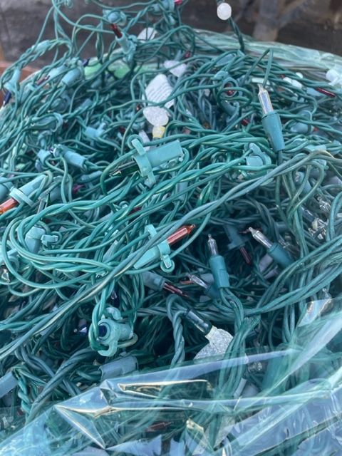 Pile of tangled green electrical cables and connectors in clear plastic packaging.