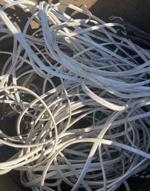 Tangled bundle of white cables and cords in a pile