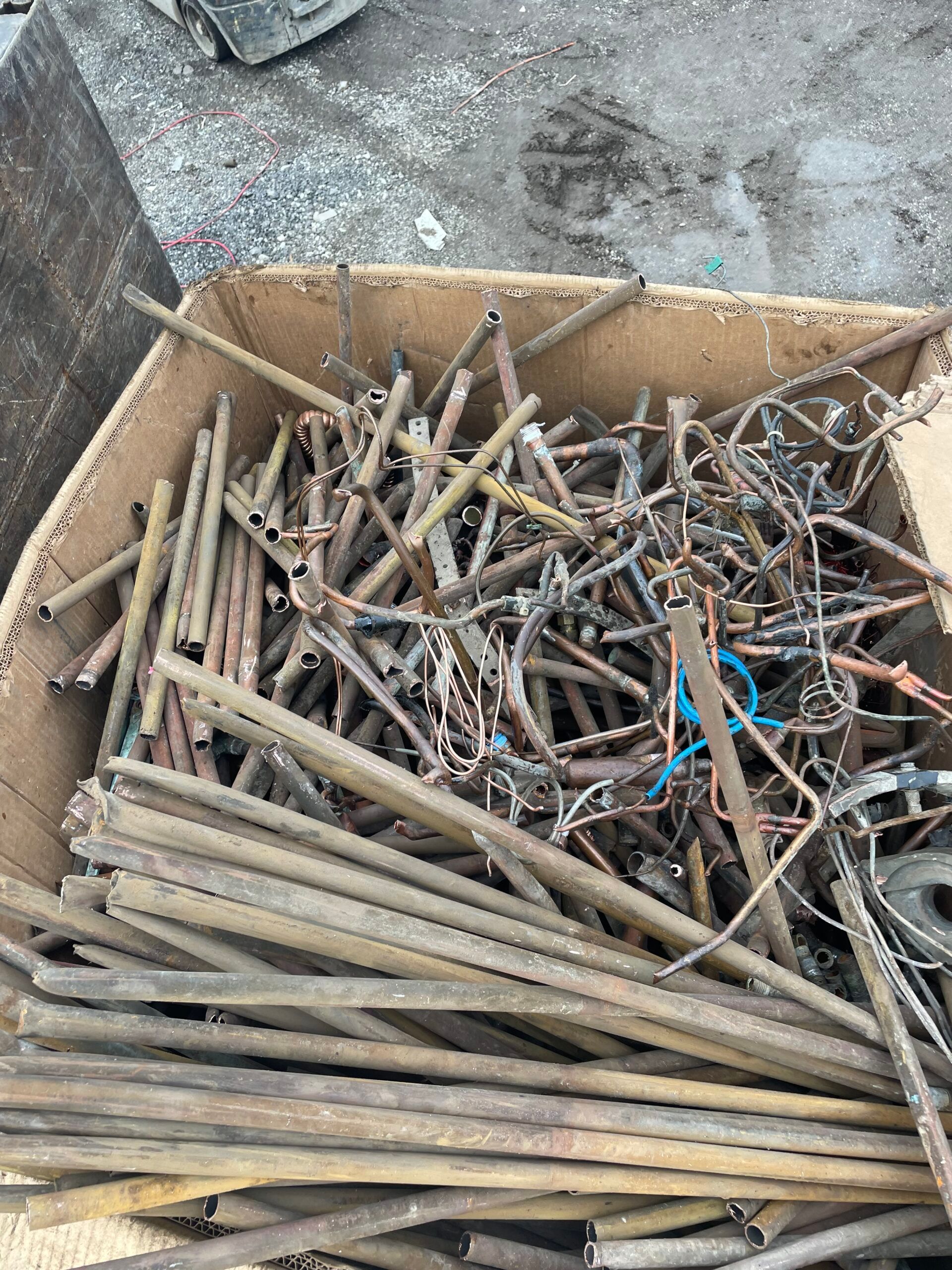 Box of mixed scrap metal rods and nails on the ground