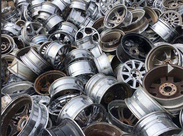 Pile of assorted metal car wheels and rims stacked together