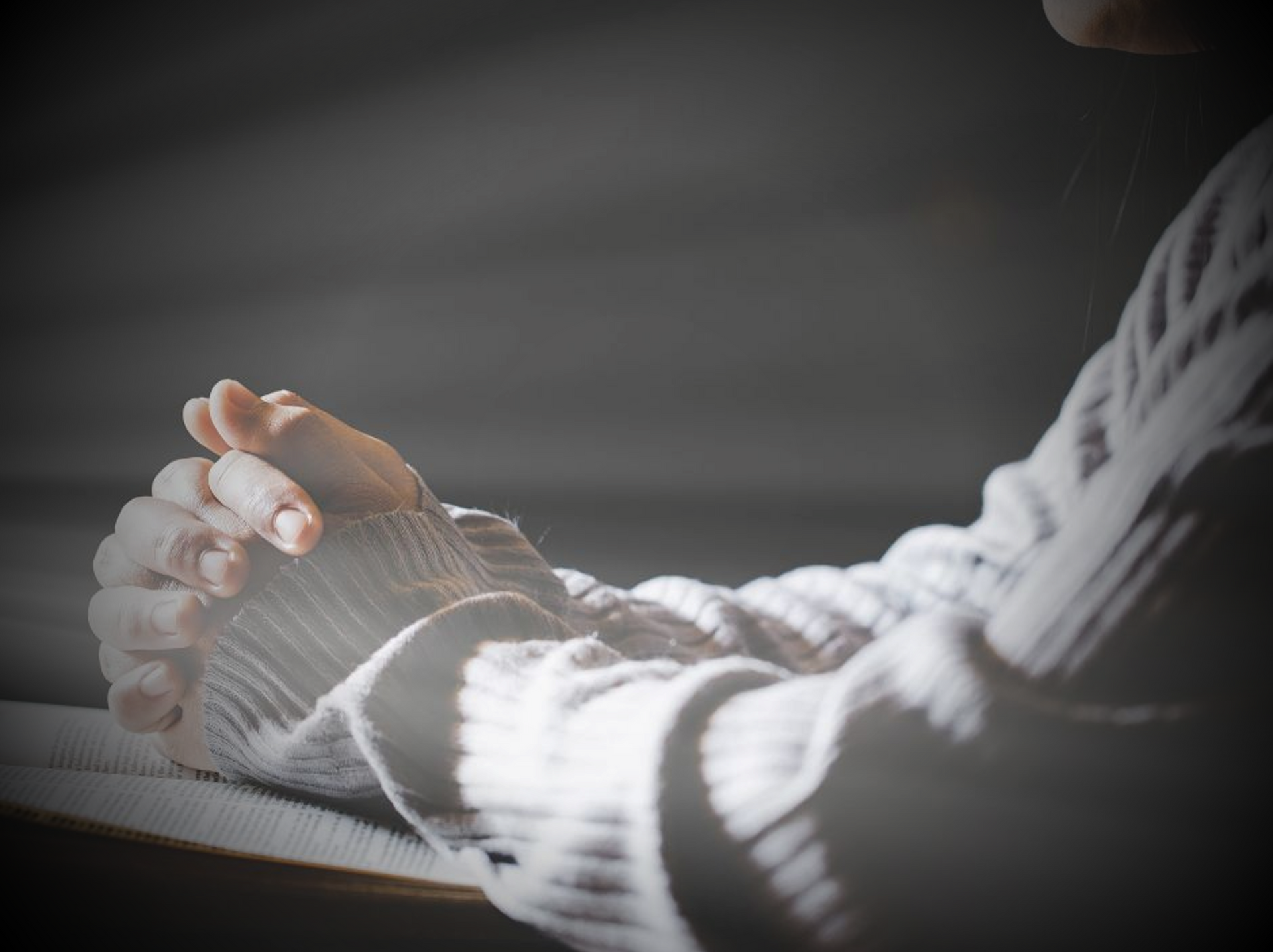 Praying hands at a table.