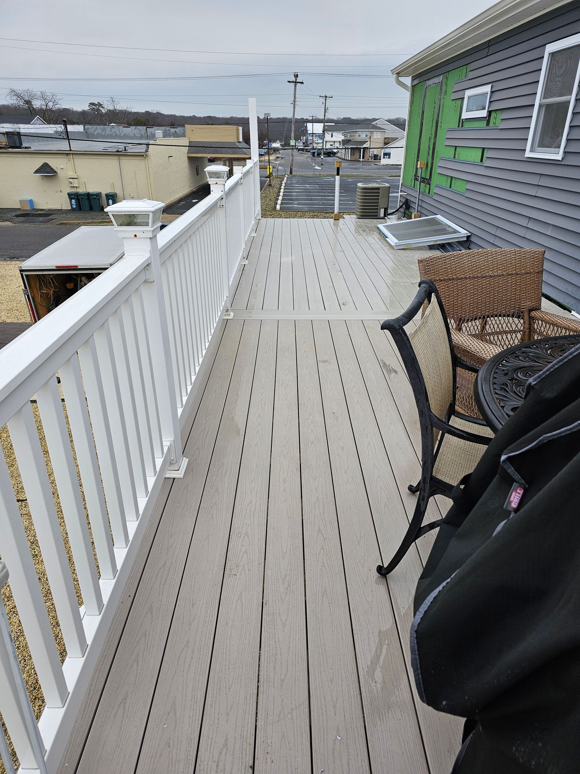 A deck with white railing, gray decking, and outdoor furniture.