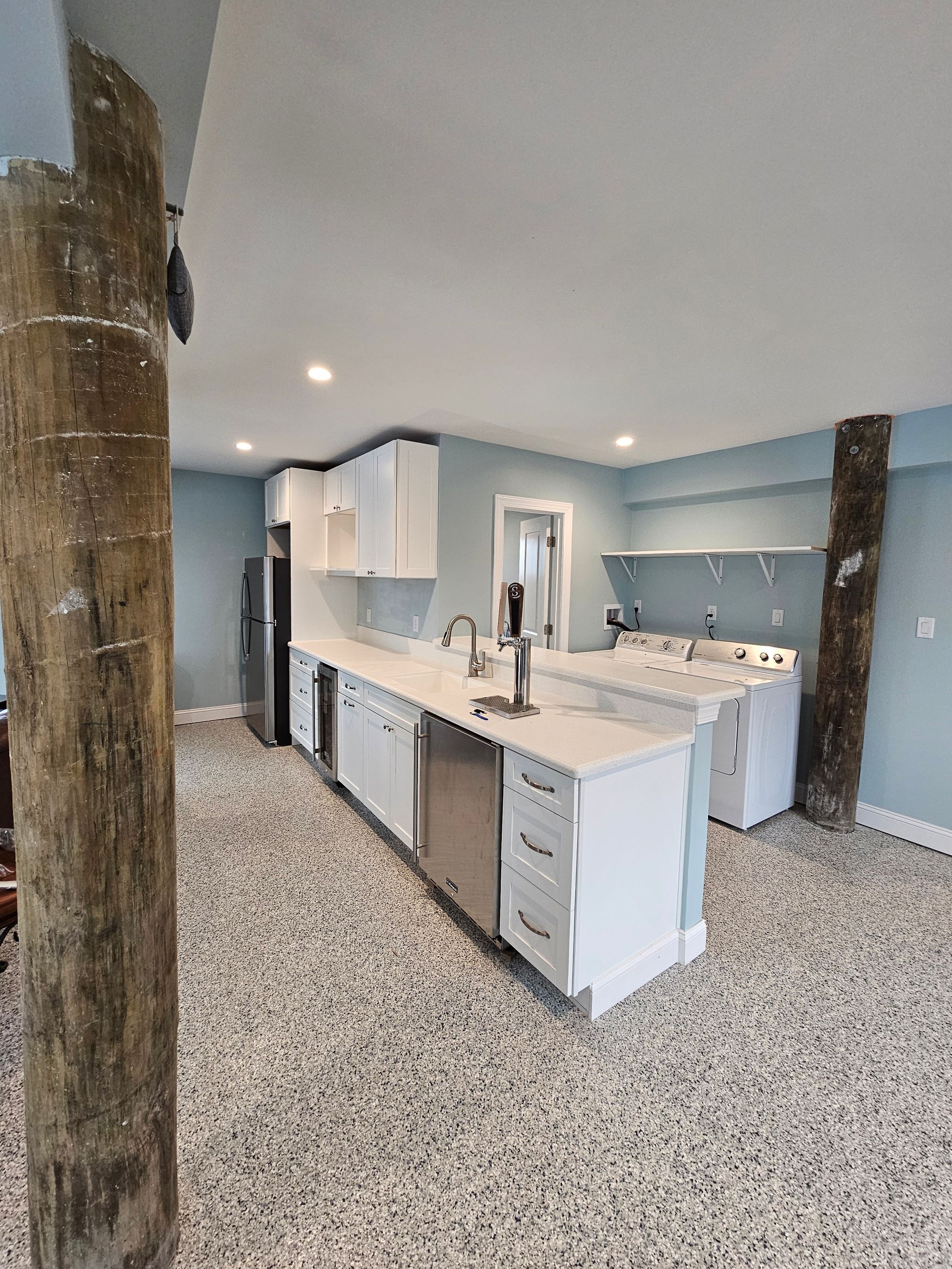 Kitchen and laundry area with white cabinets, light blue walls, and terrazzo floor.