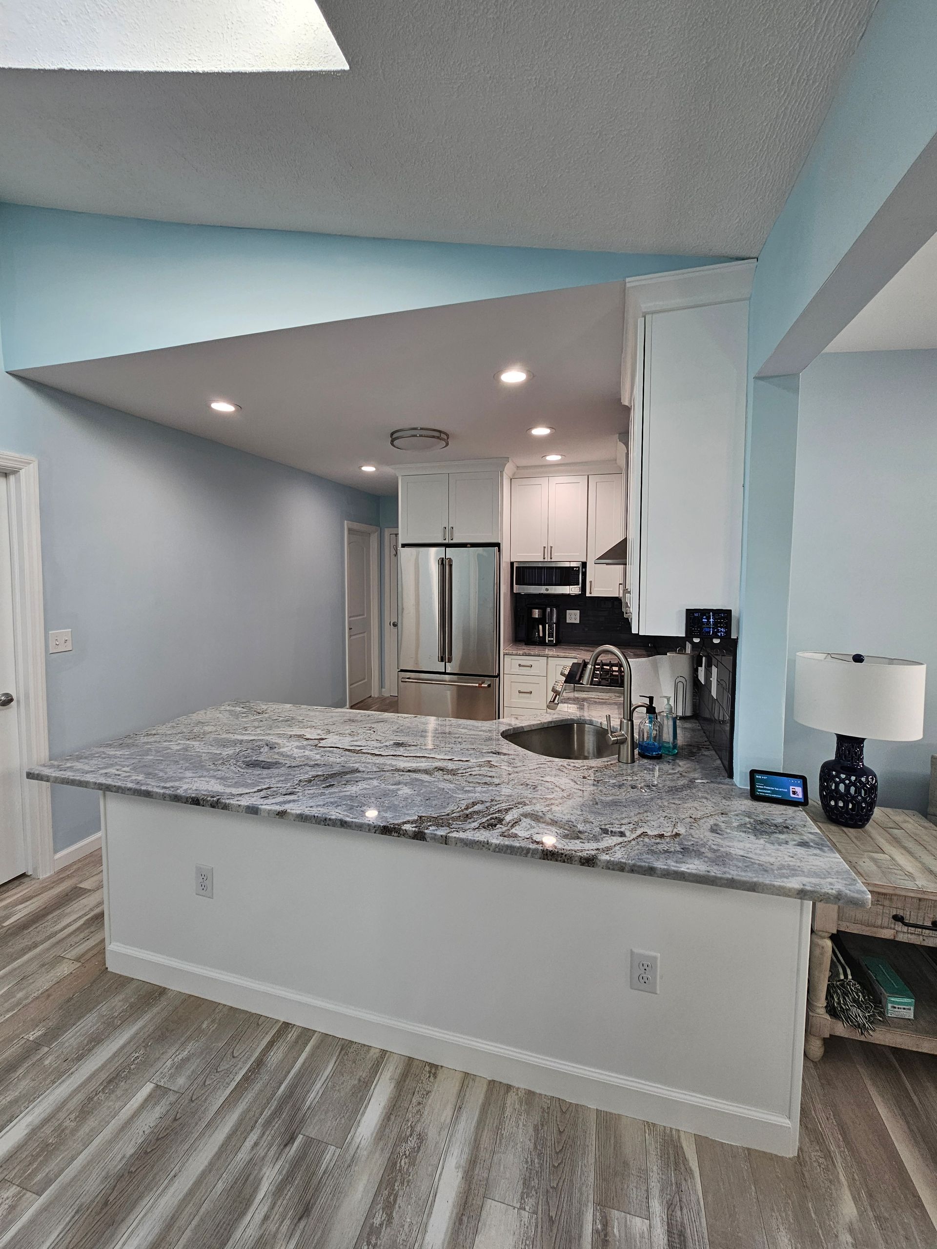 Kitchen with granite countertops, white cabinets, and pale blue walls.