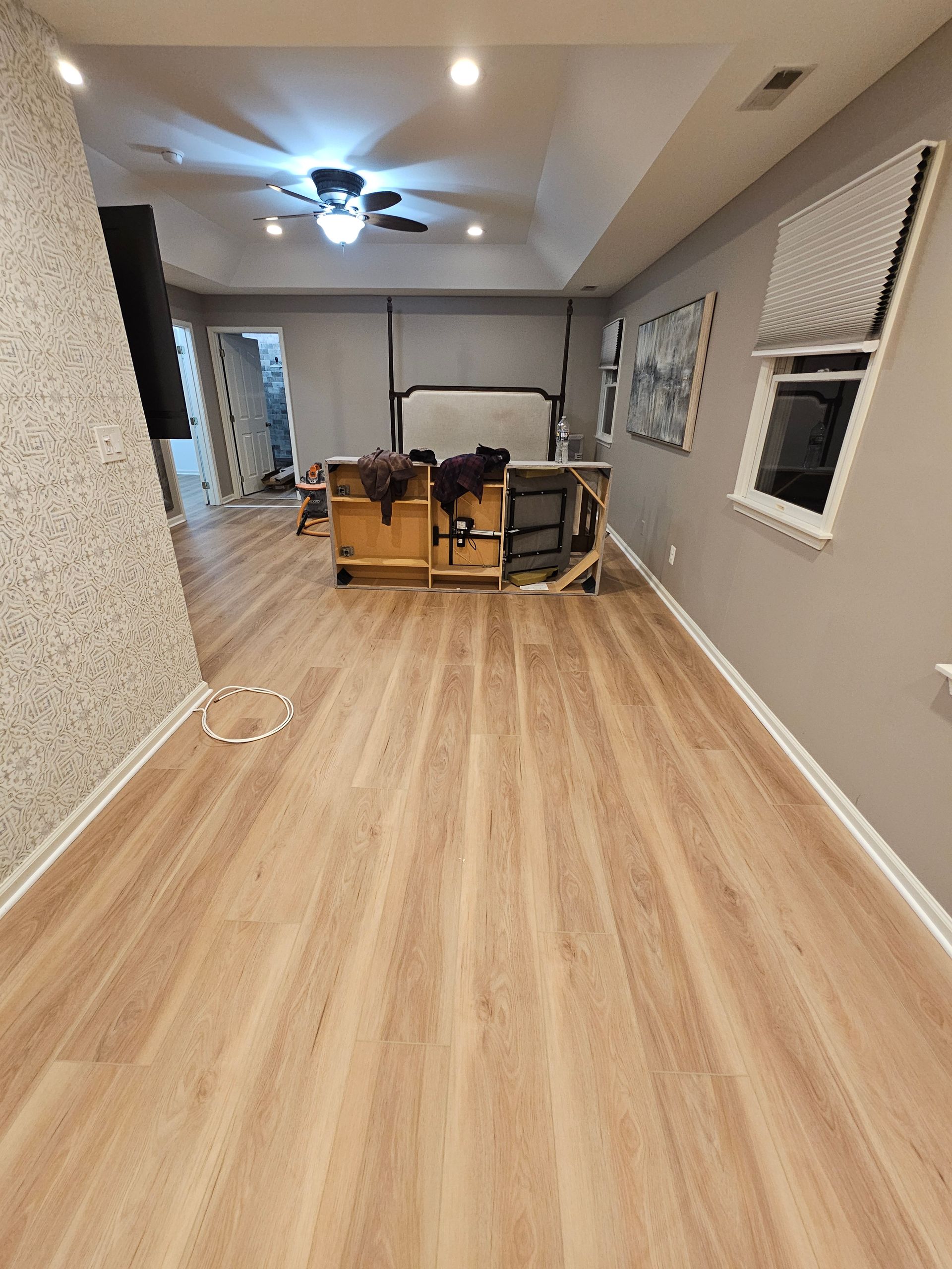 A room with wood-look flooring, gray walls, and a desk-like structure with a mounted white screen.