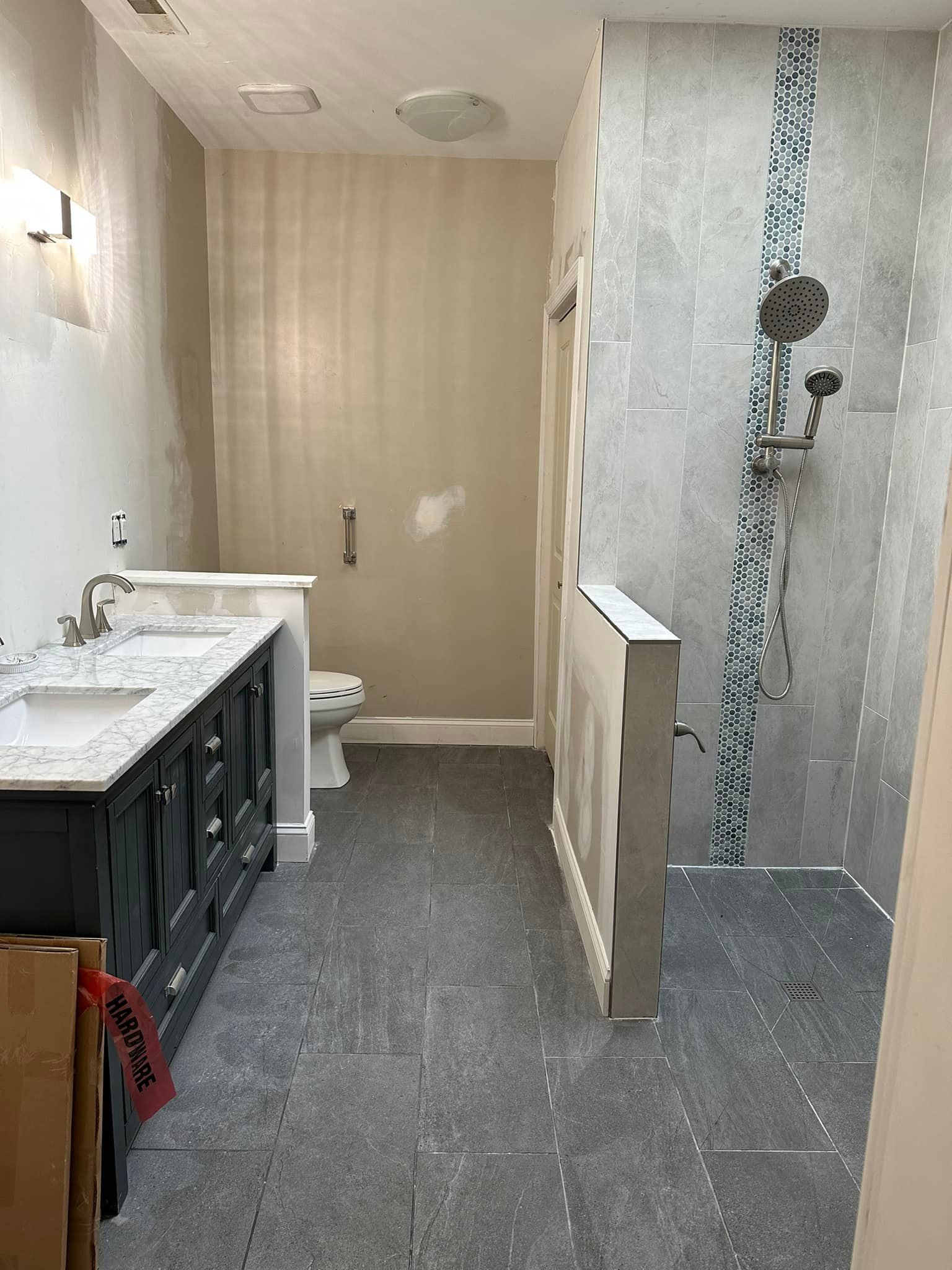 A bathroom with two sinks , a toilet , and a walk in shower.