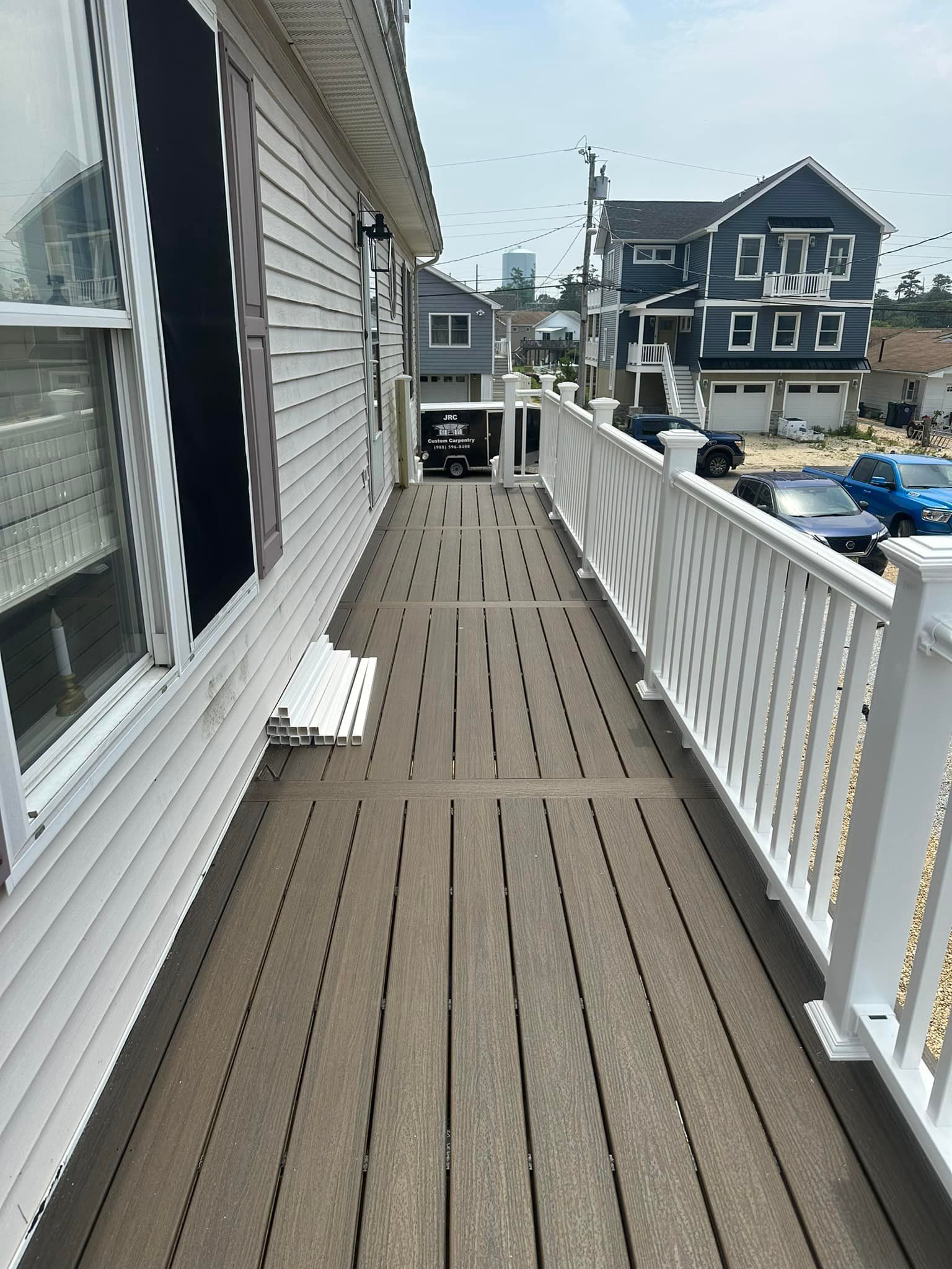 A long wooden walkway leading to a house with a white railing.