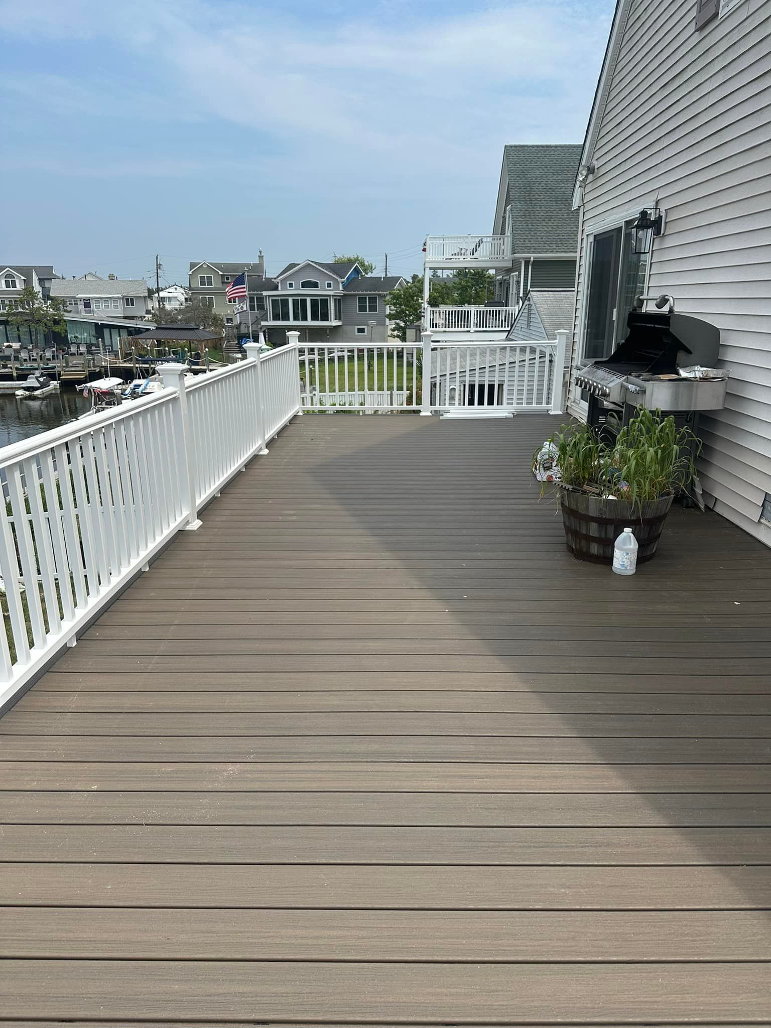 A large wooden deck with a white railing and a grill.