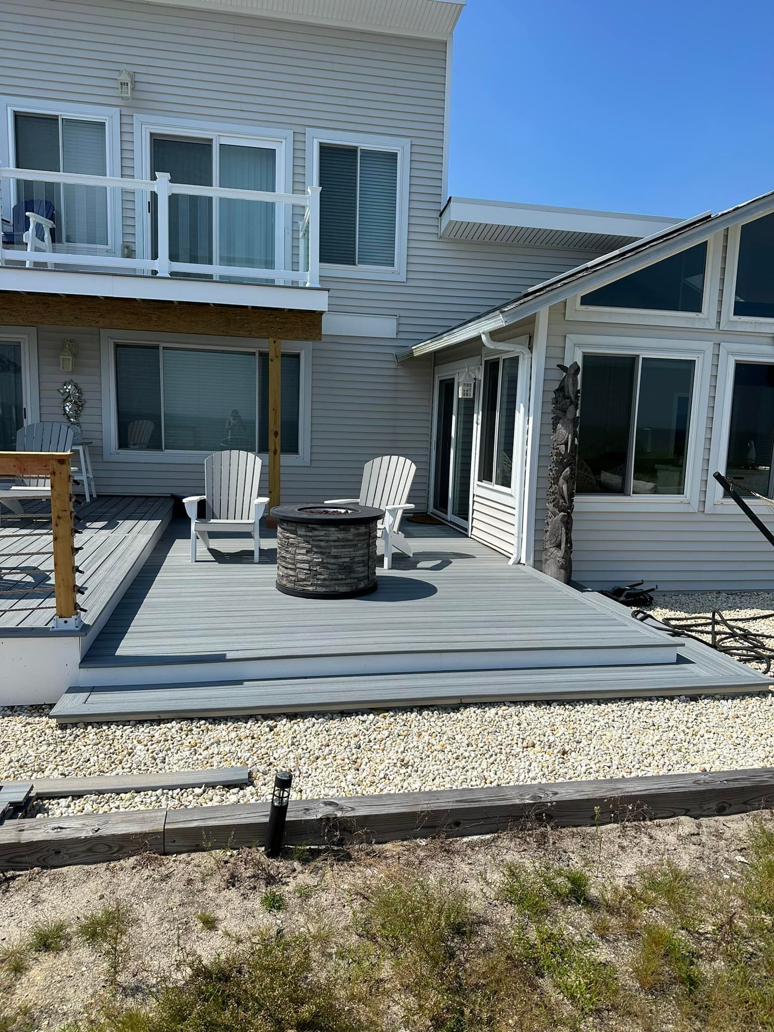 A large white house with a large deck and a fire pit.