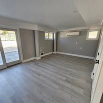 Empty room with gray walls, light gray flooring, and a large window.