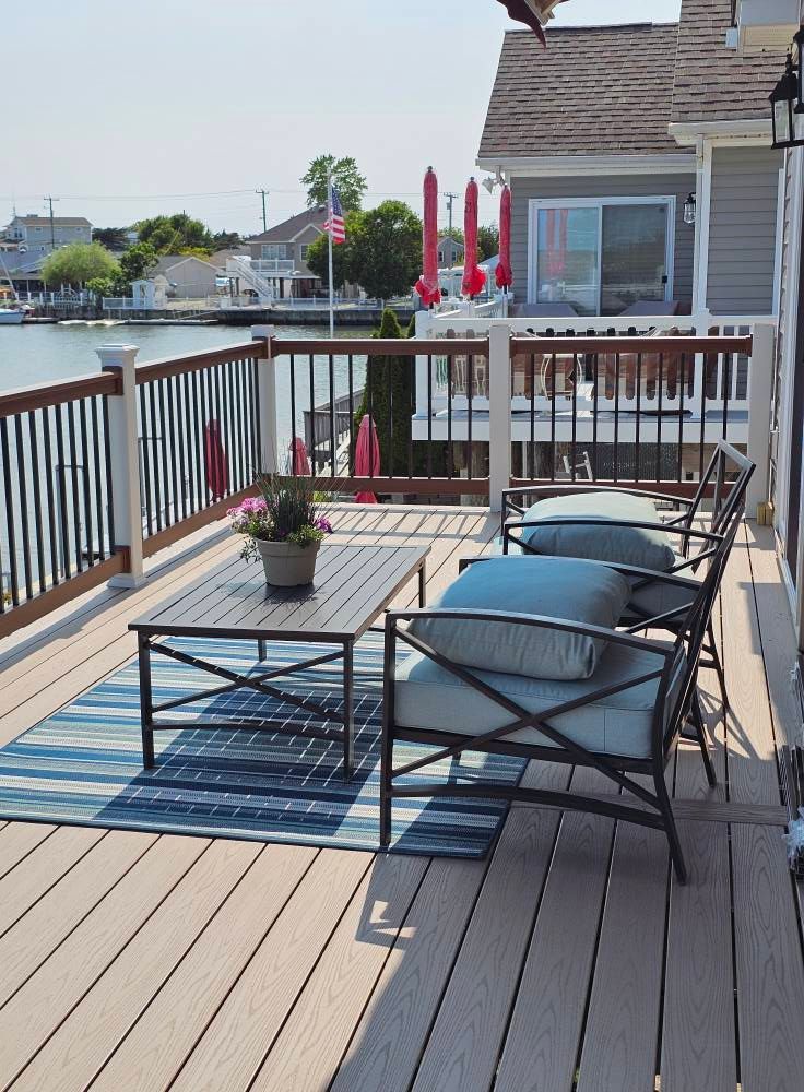 Outdoor deck with metal furniture, blue cushions, and a view of the water.