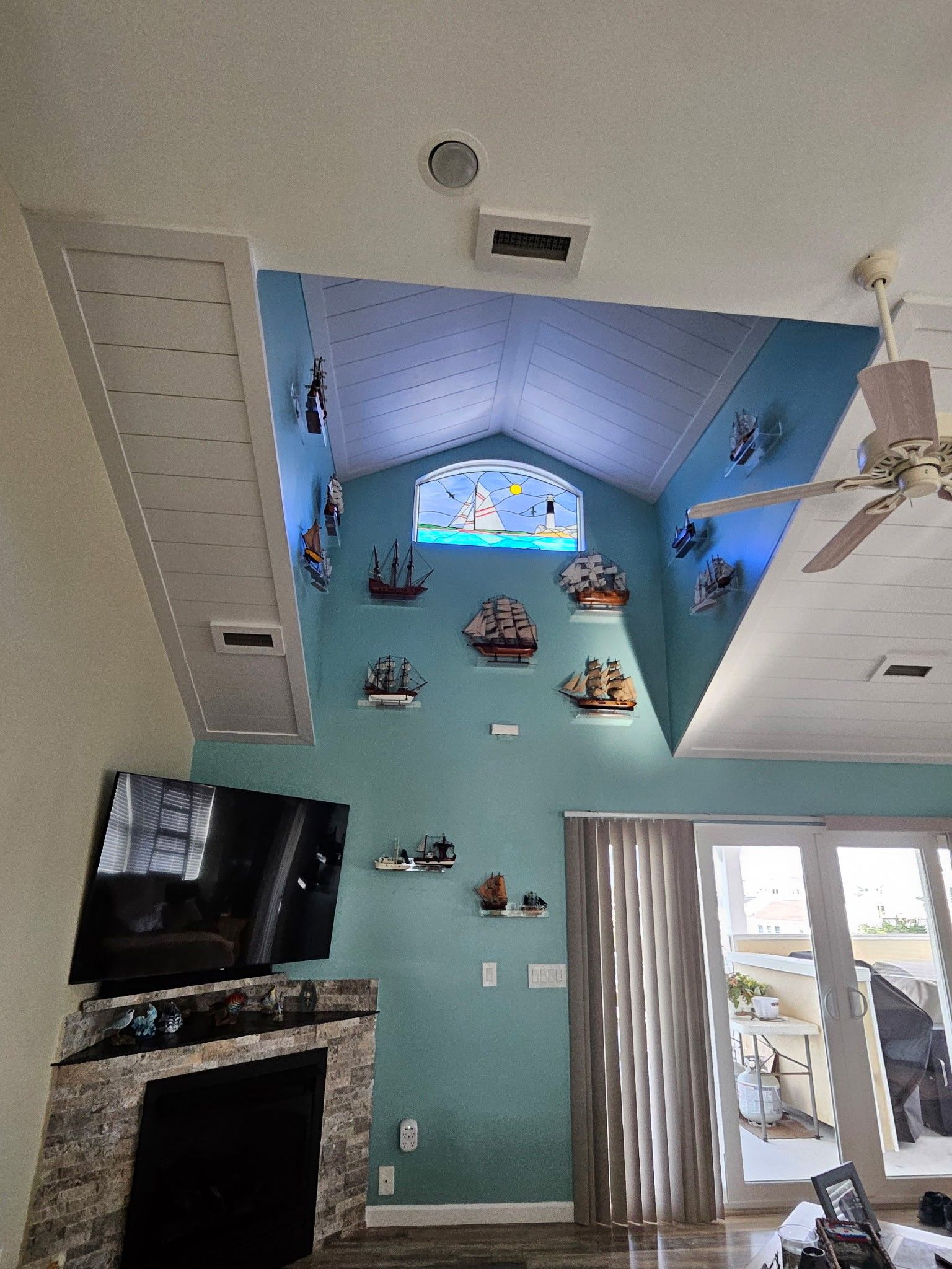 Living room with ship-themed wall decor, fireplace, TV, and doors leading outside.