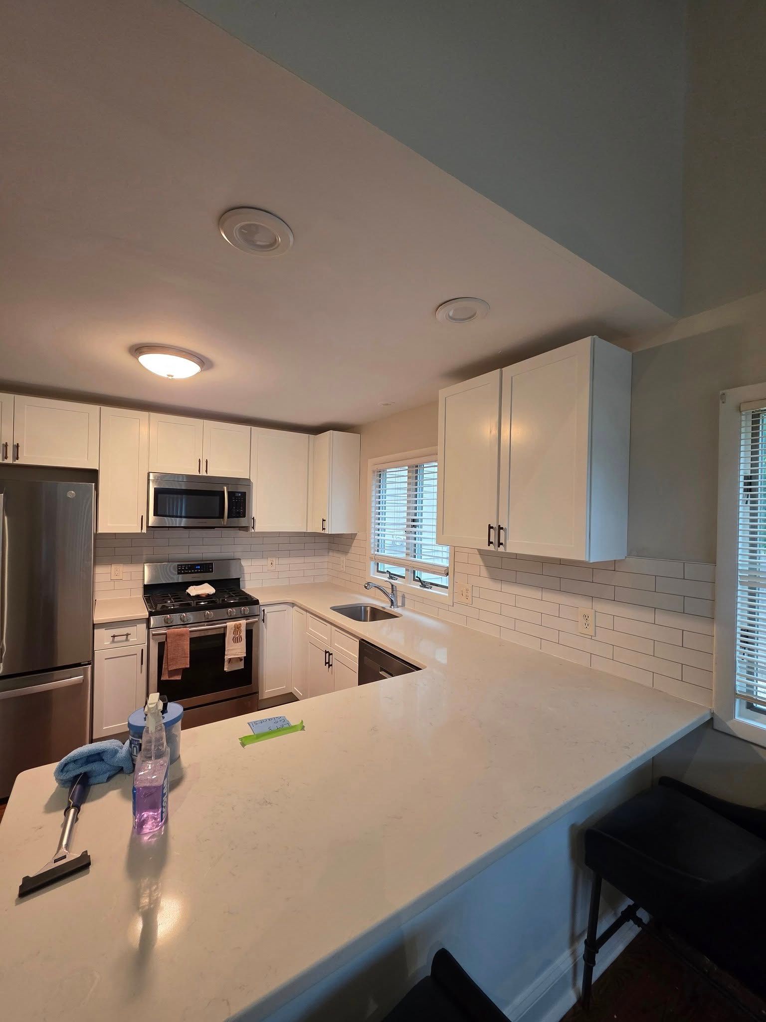 White kitchen with countertops, cabinets, appliances, and a tiled backsplash.