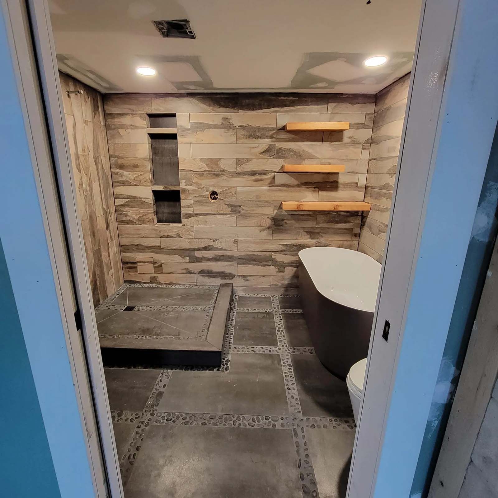 A bathroom with a tub , toilet , shower and shelves.