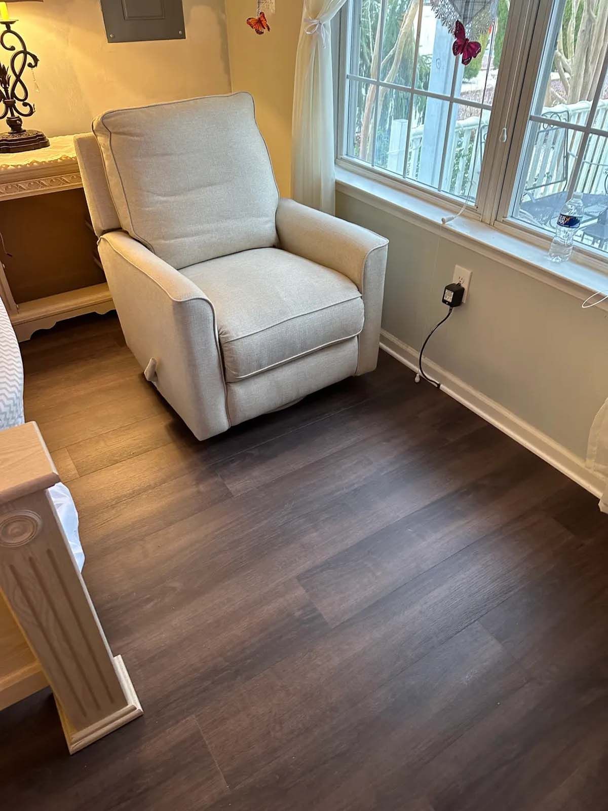 A white recliner is sitting in a living room next to a window.
