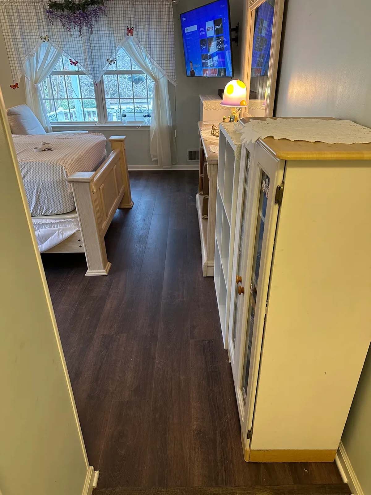 A bedroom with a bed , dresser , mirror and television.