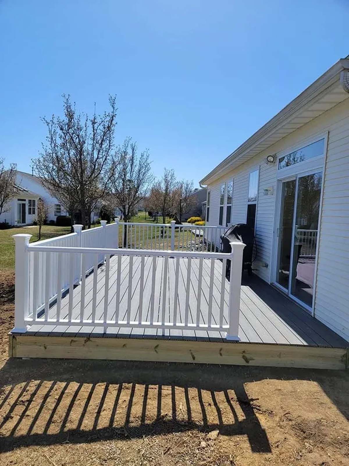 A white house with a large deck and sliding glass doors.