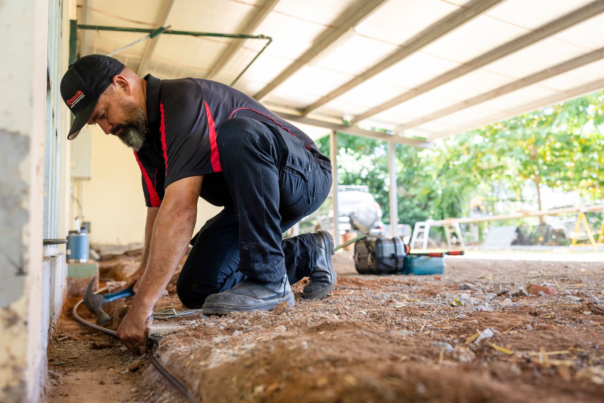 A Man Laying Down Bate on Dirt  — Quack Pest Control in Winnellie, NT
