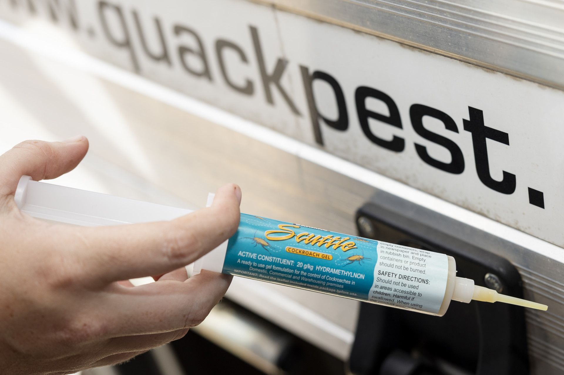 Person Injecting Pesticide From a Syringe Near a Sign That Reads www.quackpest.com.au — Quack Pest Control in Fannie Bay, NT