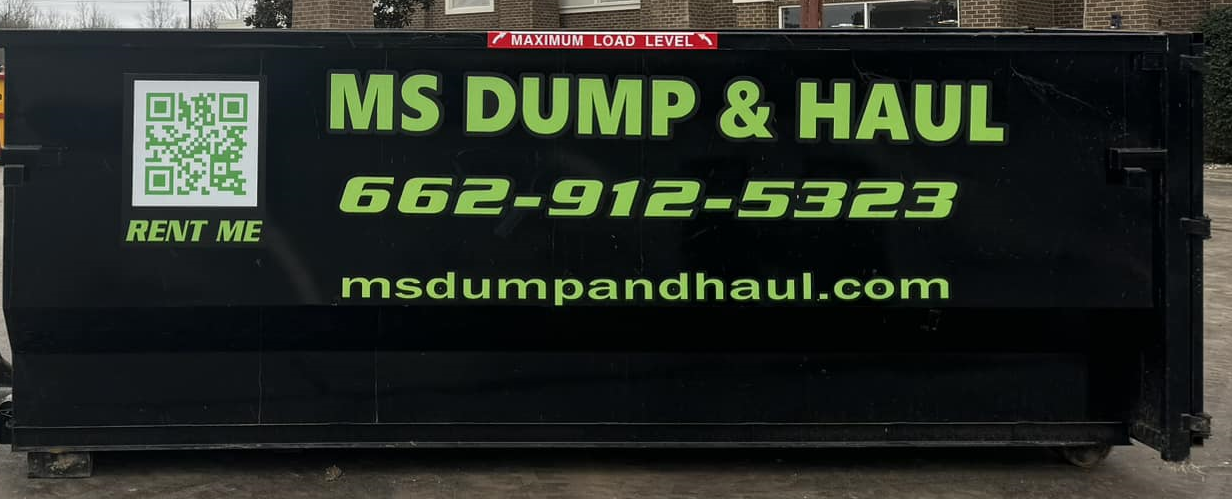 A dumpster is parked in front of a brick house.