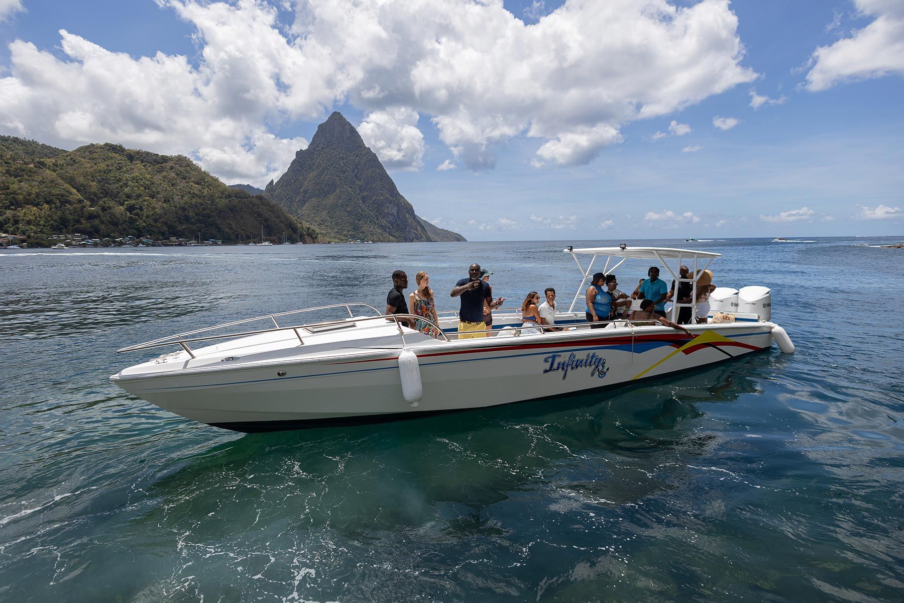 Tourist on a white speedboat on blue water near a tropical island and mountain