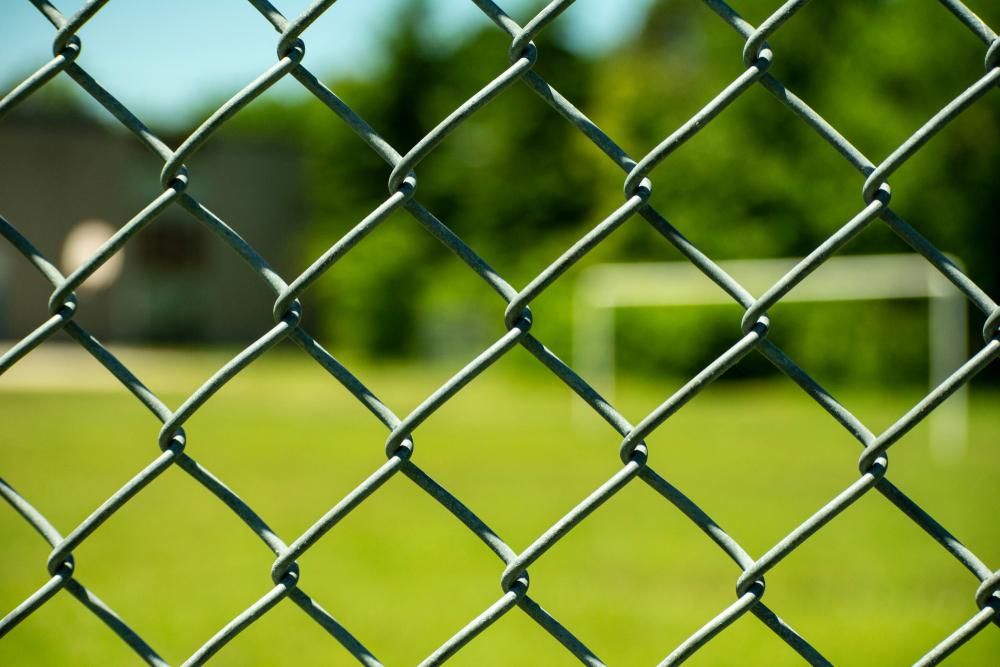 A Chain Link Fence with A Soccer Goal in The Background — Byron & Beyond Fencing In Billinudgel, NSW