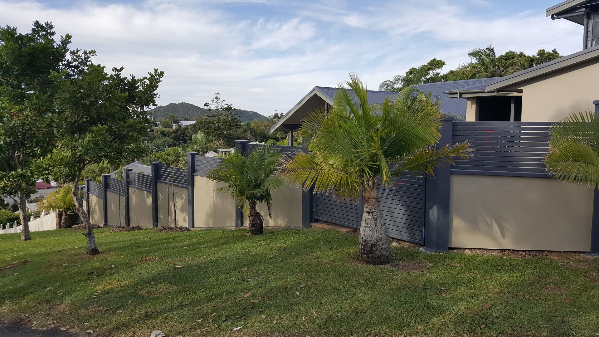 A Wooden fence running along the right side of a white house — Byron & Beyond Fencing In Billinudgel, NSW