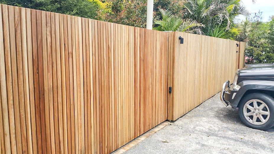 A Car Is Parked in Front of A Wooden Fence — Byron & Beyond Fencing In Billinudgel, NSW 