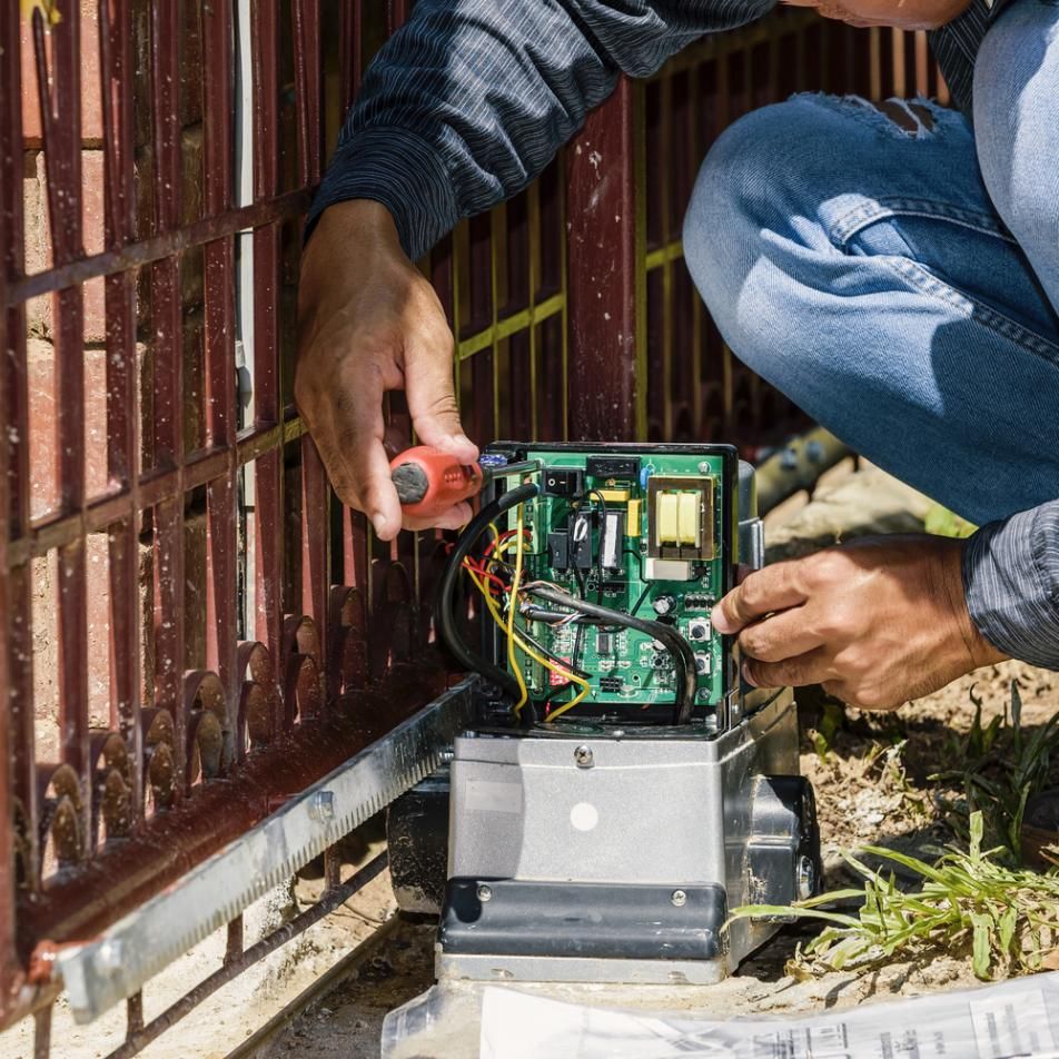 A Man Is Fixing a Sliding Gate with A Screwdriver — Byron & Beyond Fencing In Billinudgel, NSW