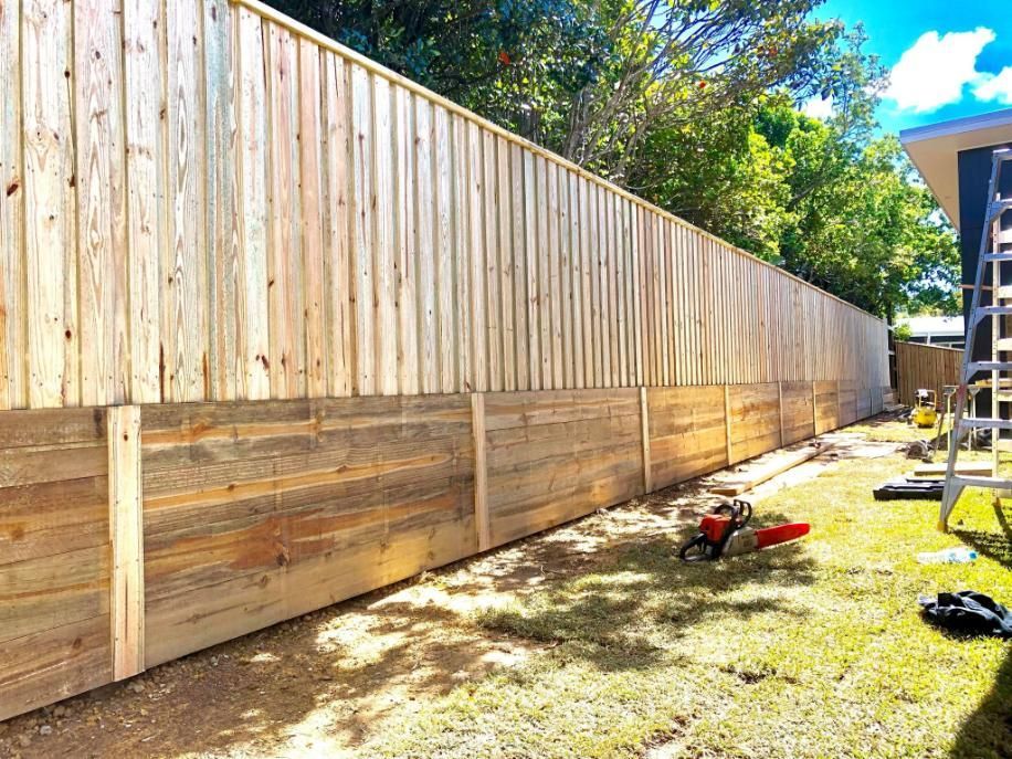 Wooden fence in a yard with a chainsaw on the ground.