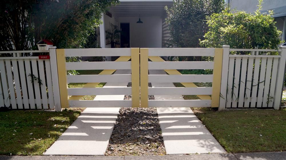 A White Fence with A Yellow Gate in Front of A House — Byron & Beyond Fencing In Billinudgel, NSW